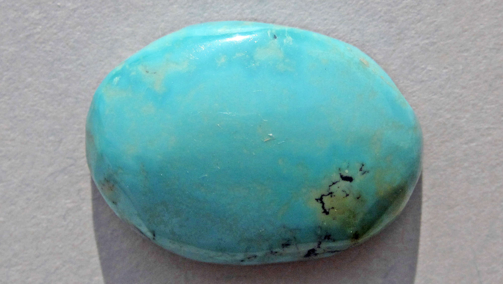 pierre de turquoise cabochon sur fond beige pour illustrer la turquoise bleue