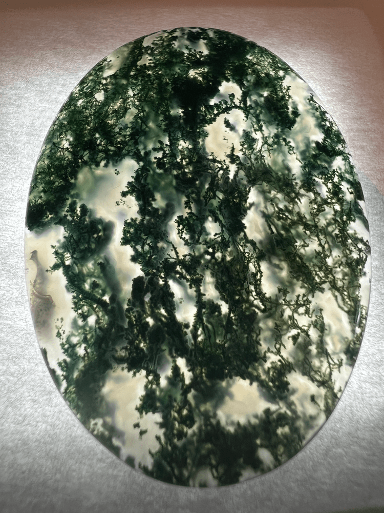 green moss agate stone on neutral background to illustrate a green gemstone