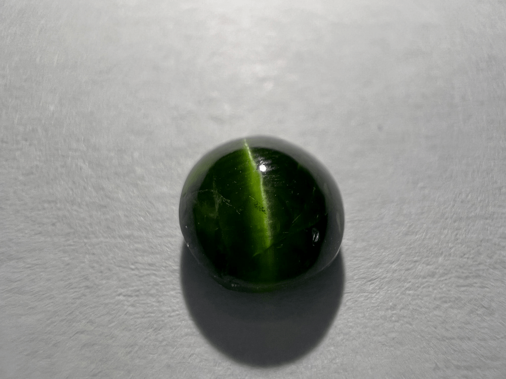 pierre verte de diopside chrome oeil de chat sur fond neutre pour illustrer une pierre verte