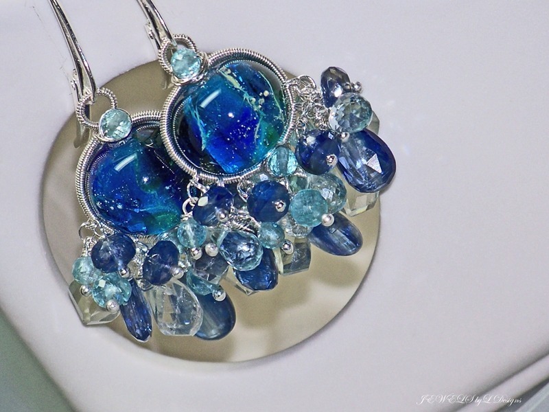 deux boucles d'oreille faites en verre soufflé bleu et kyanites, tenues par des fils en argent sterling pour illustrer la portabilité de la kyanite