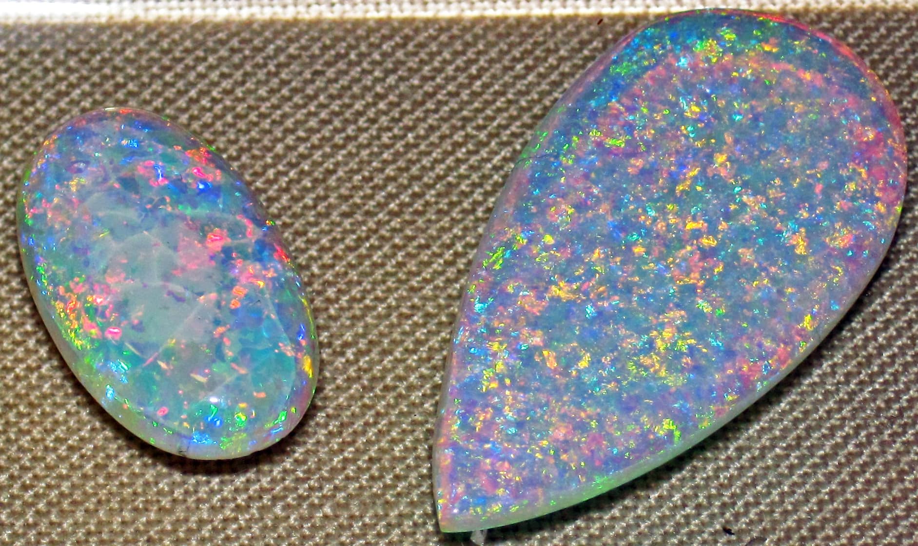 deux opales précieuse blanches d'australie montrant leurs feux multicolores sur fond beige pour illustrer l'opale blanche