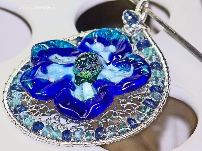 pendentif en argent sterling avec une fleur en verre soufflé bleue au centre et entouré de plein de petites billes de kyanite et d'apatite pour illustrer les bijoux en kyanite
