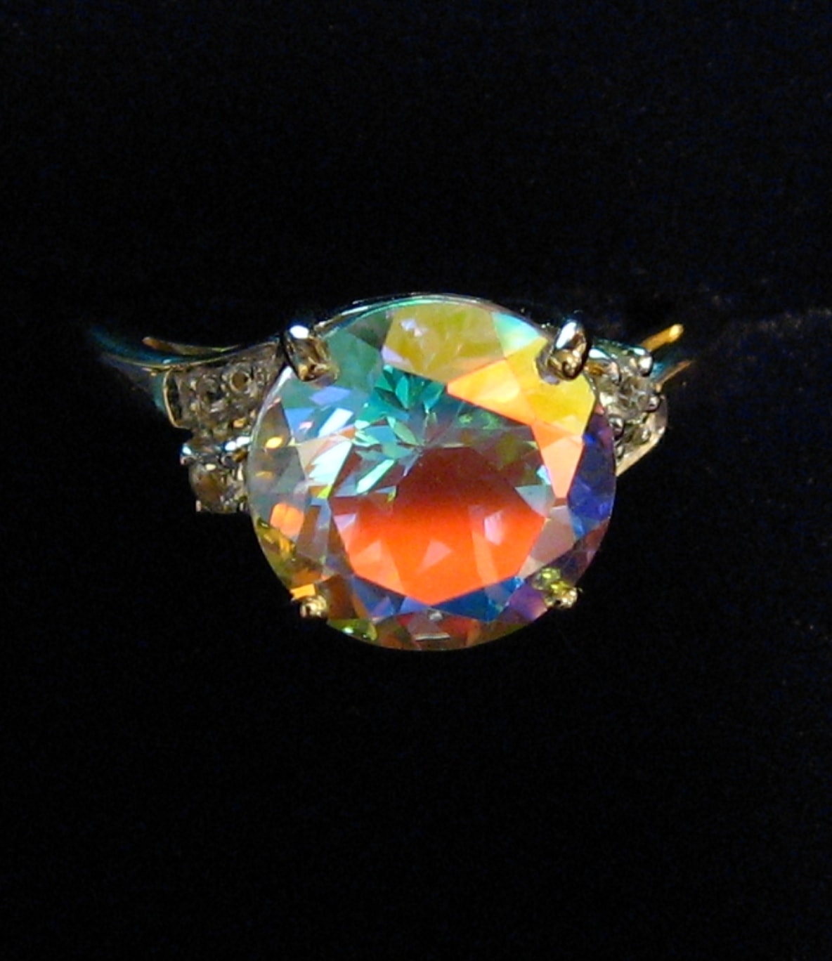 ring with a central mystic topaz showing its various flashes of bright colors to illustrate the mystic topaz 