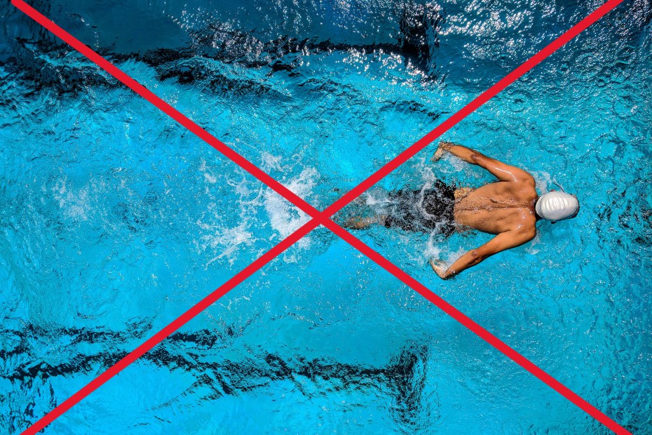 piscine municipale vue du dessus avec l'eau bleue claire et un nageur masculin faisant du papillon pour illustrer les gemmes à ne pas porter à la piscine