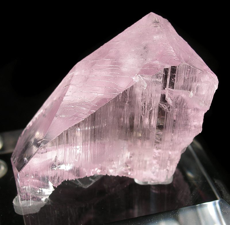 crystal de spodumène de variété kunzite rose pastel transparent montrant sa structure cristalline par des facettes droites et des angles précis.