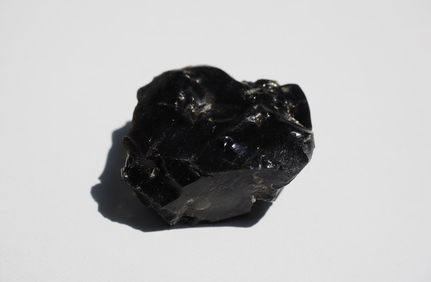 morceau d'obsidienne noire sur fond blanc pour illustrer l'obsidienne