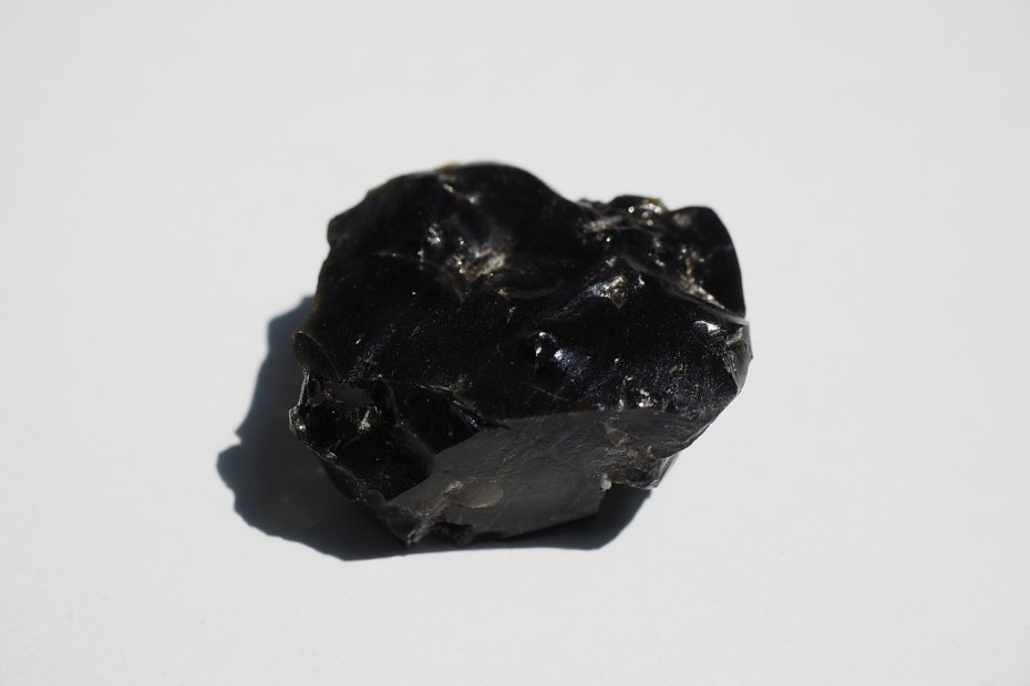 morceau d'obsidienne noire sur fond blanc pour illustrer l'obsidienne