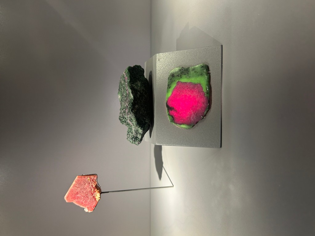 trois cristaux sont présentés. Un rubis tranché rouge à gauche, un morceau de roche d'anyolite, aussi connu comme rubis dans la zoïsite. Et une tranche de cette anyolite montrant le contour en vert et le milieu hexagonal rouge vif.